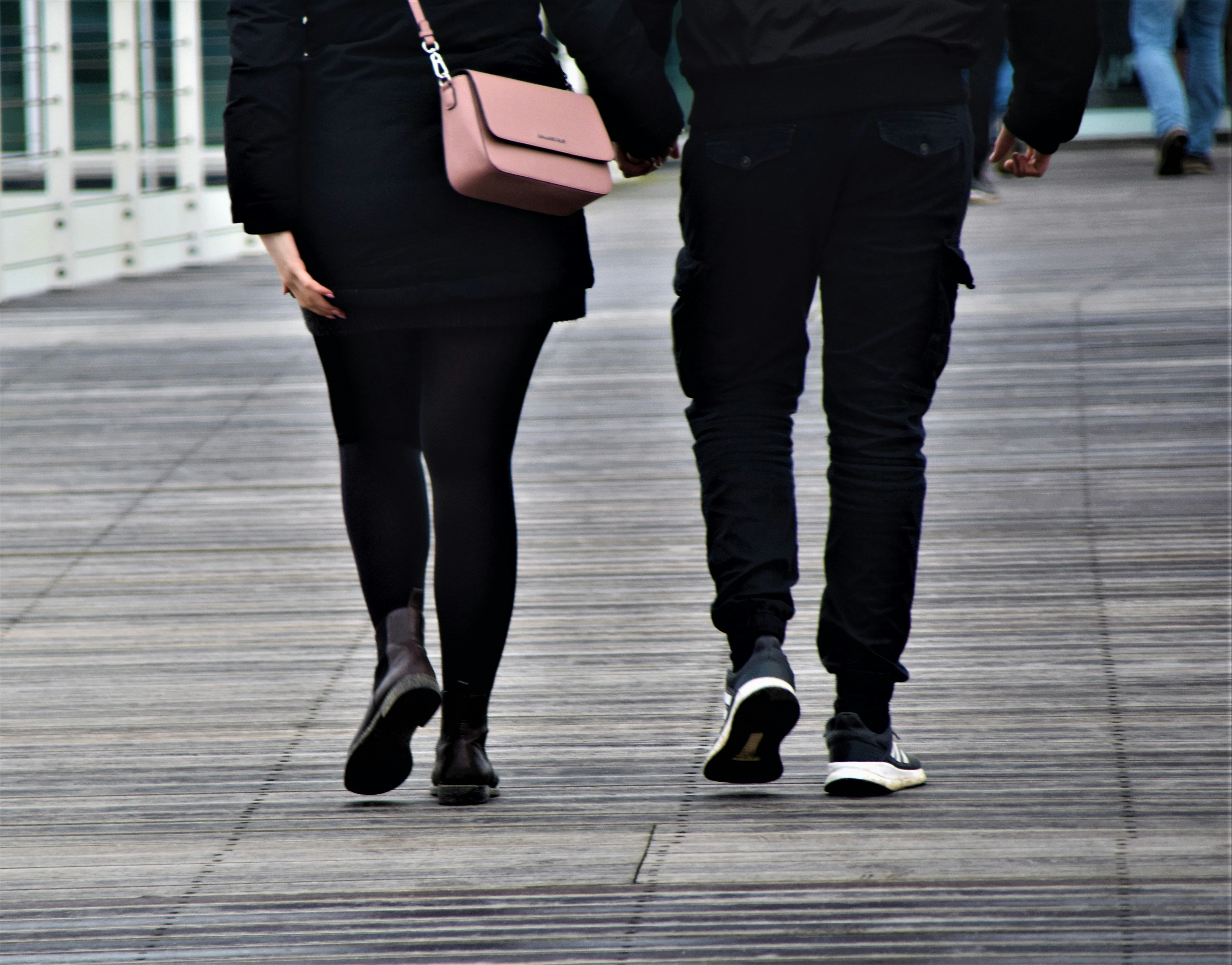 woman in black pants and black leather boots holding brown leather sling bag